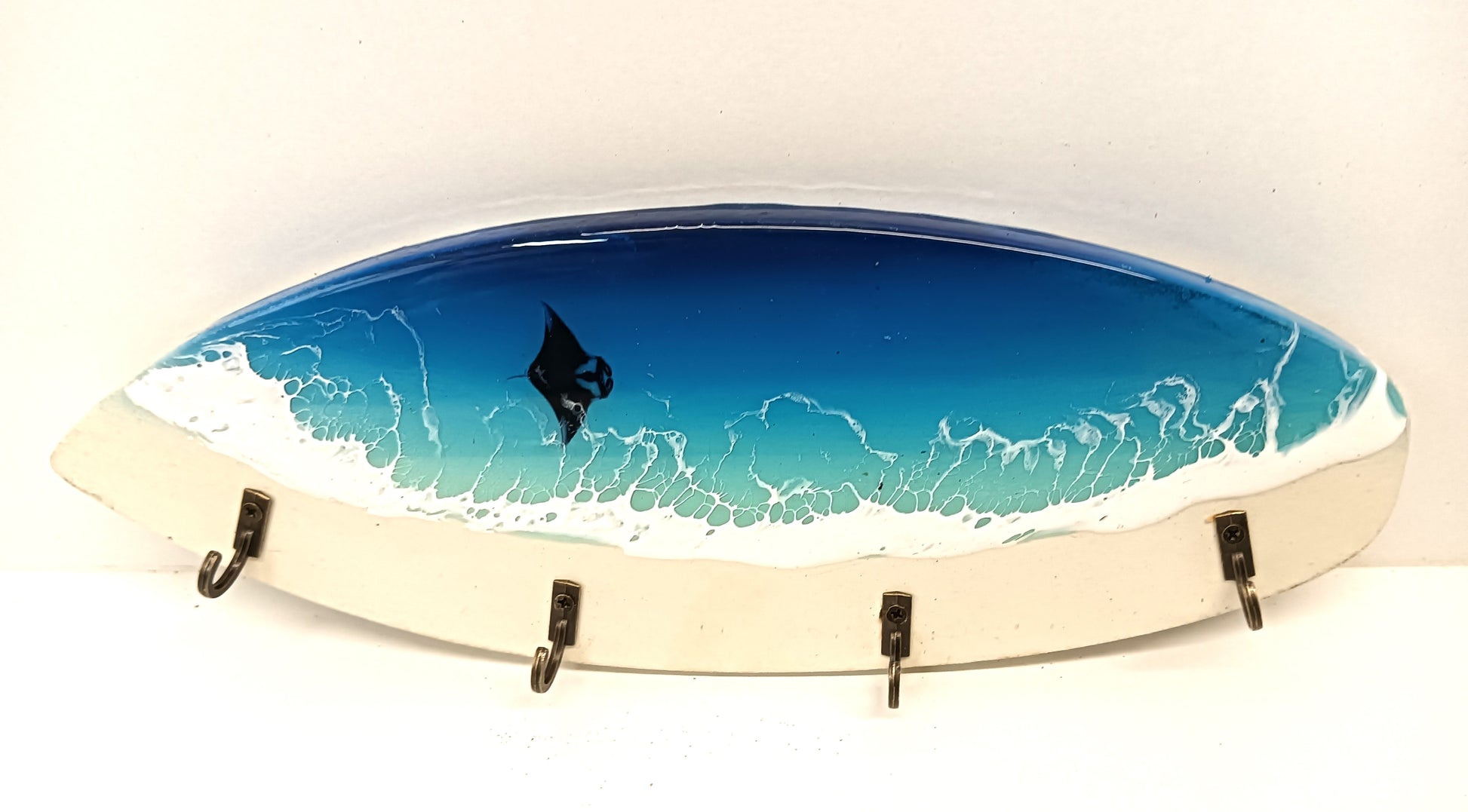 Handmade surfboard key holder featuring ocean resin art, with four key hooks, showcasing unique wood grain and design variations.